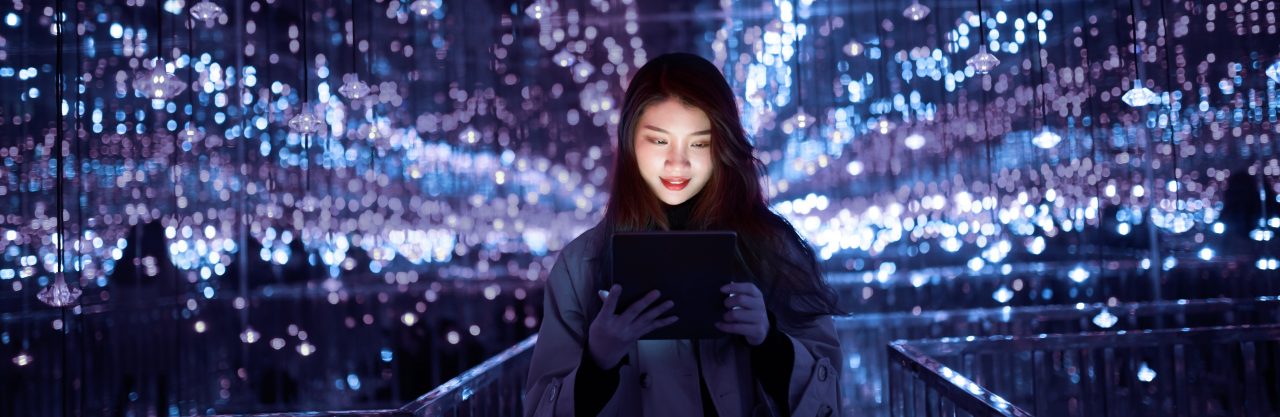girl on purple and black background looking at a tablet