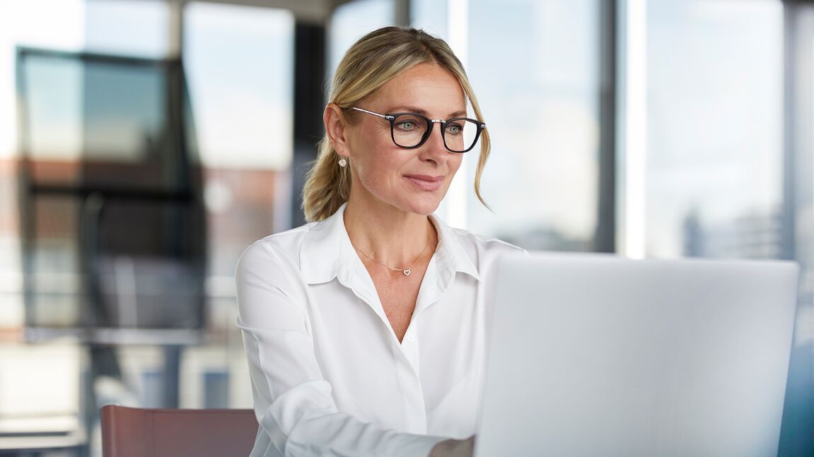 Smiling businesswoman typing on computer in modern office