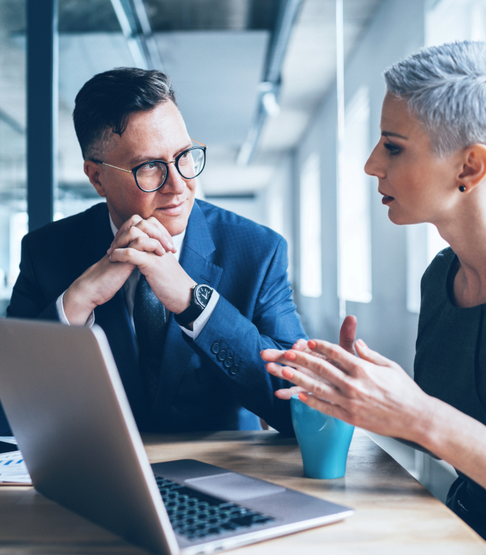 Two colleagues working together next to laptop in conference room