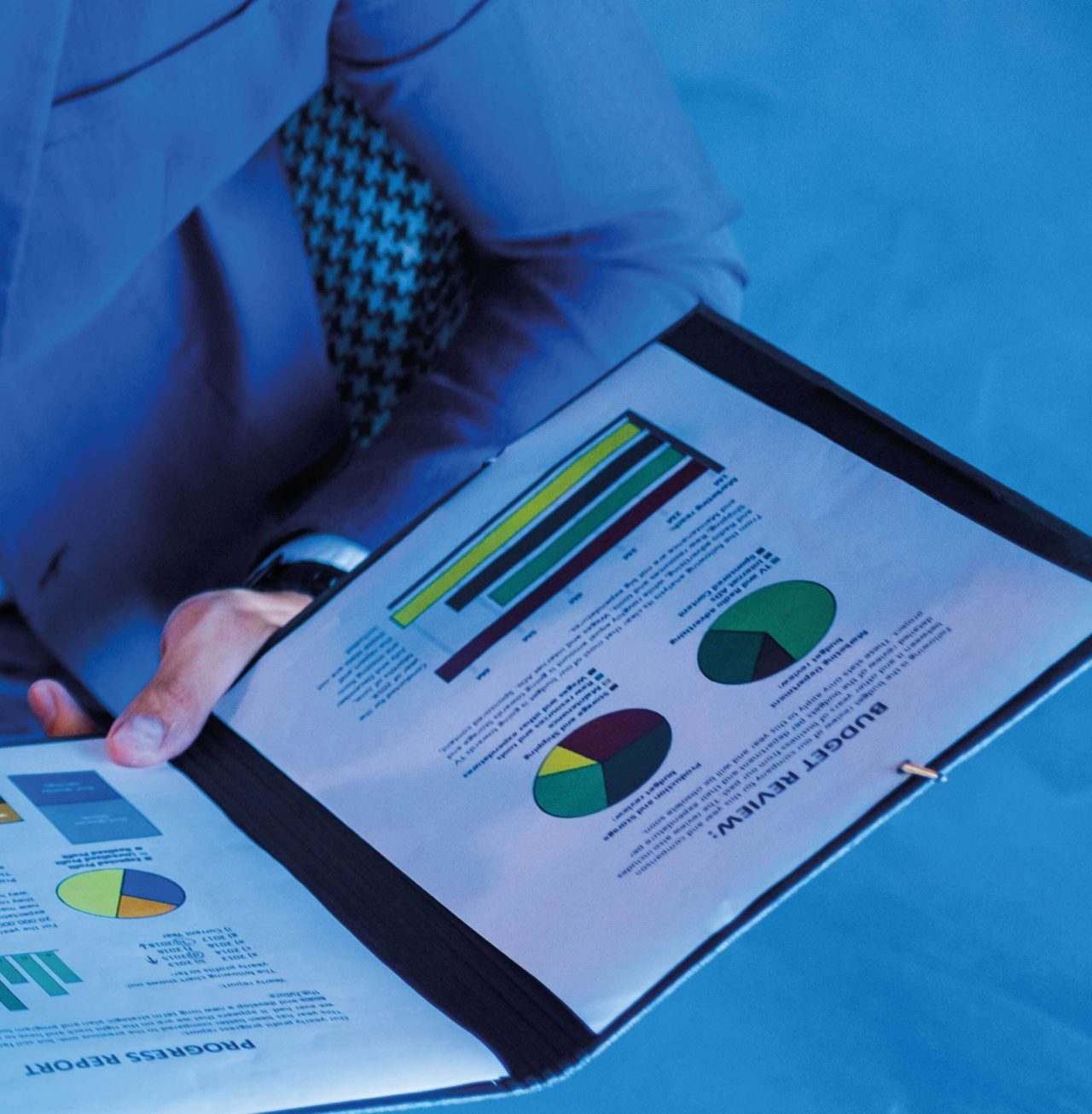 Continuation of businessman sitting at desk holding open folder with documents
