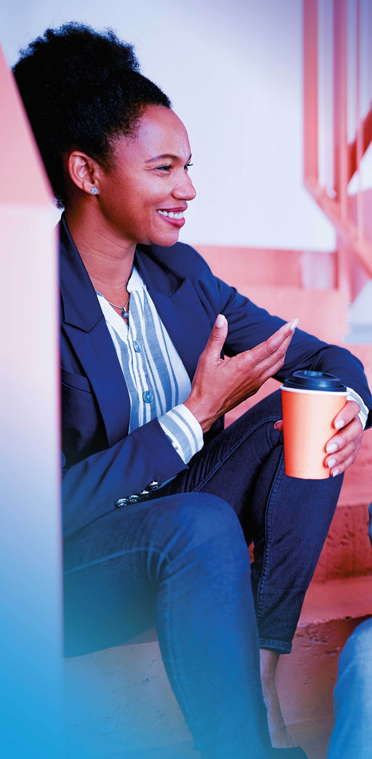 Two coworkers chatting while drinking coffee while sitting on a stairwell