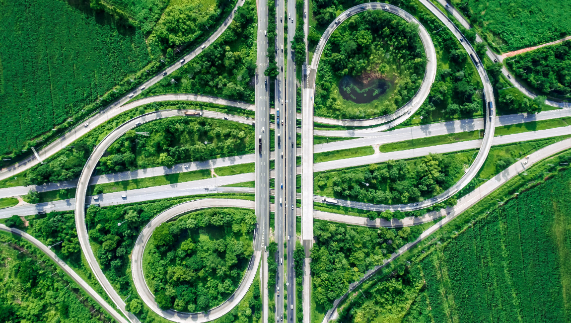 Aerial view of multiple highways merging surrounded by green grasses and trees