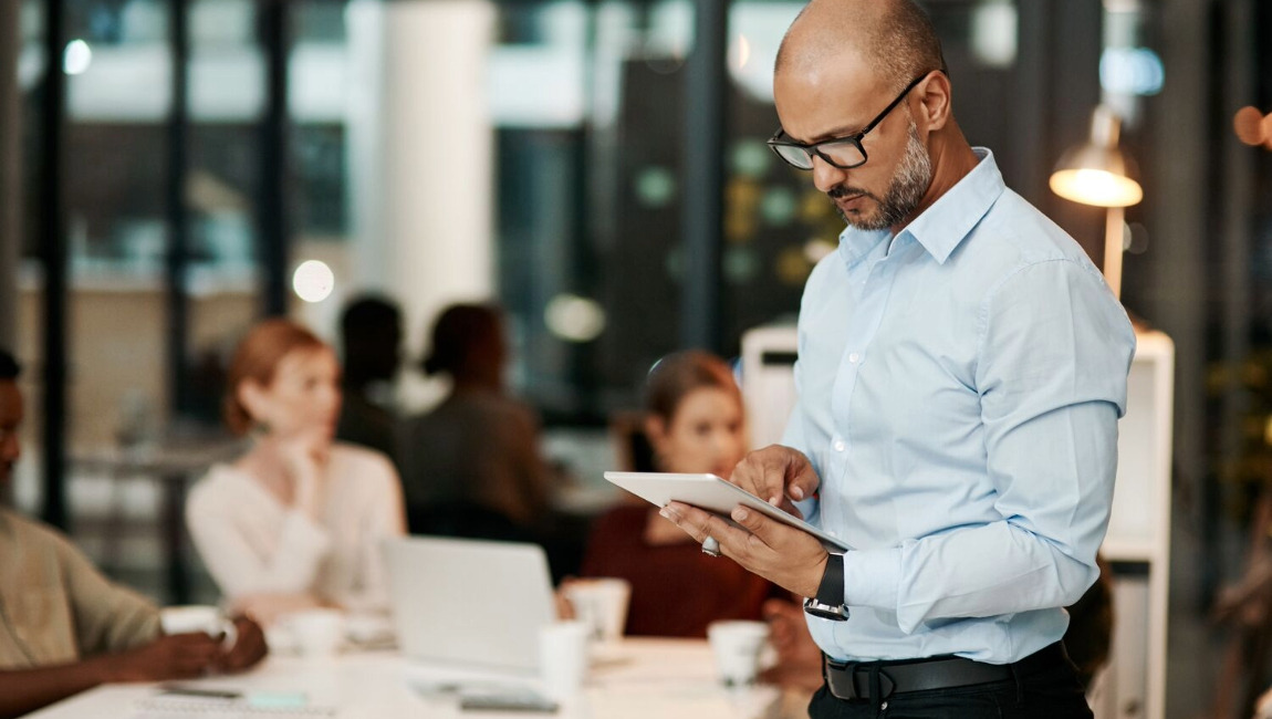 Businessman standing in an office reading a tablet