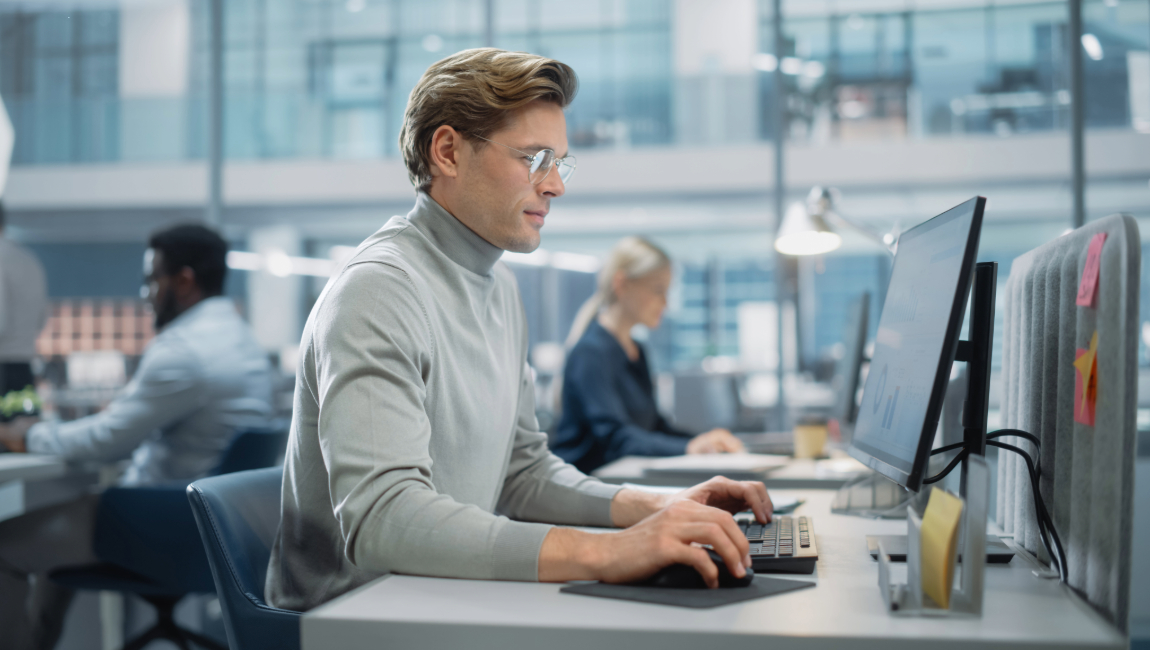 Man wearing turtleneck working on computer in modern office builiding