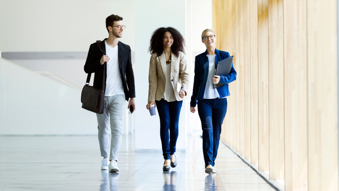 Three happy coworkers walking in lobby of trendy office building