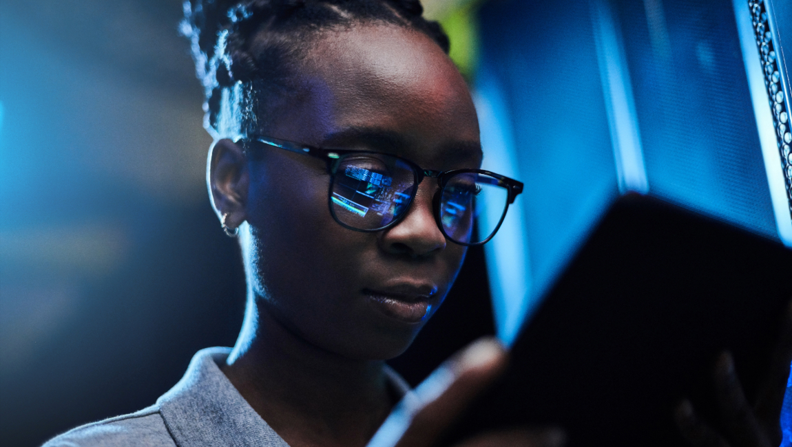 Business woman looking at a tablet in a server room