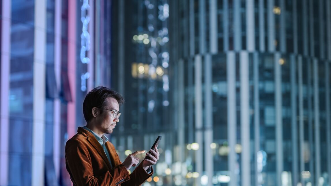 Businessman looking at cellphone amid busy city backdrop