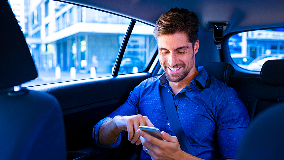 Man riding in taxi looking at his phone