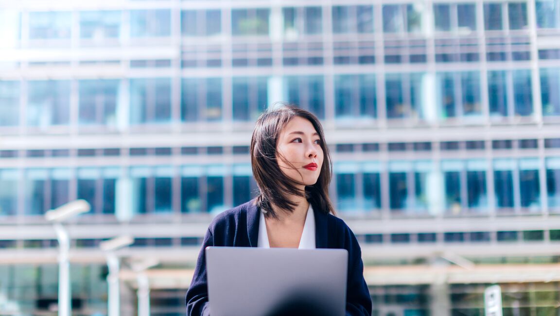 Businesswoman working with laptop outside office building