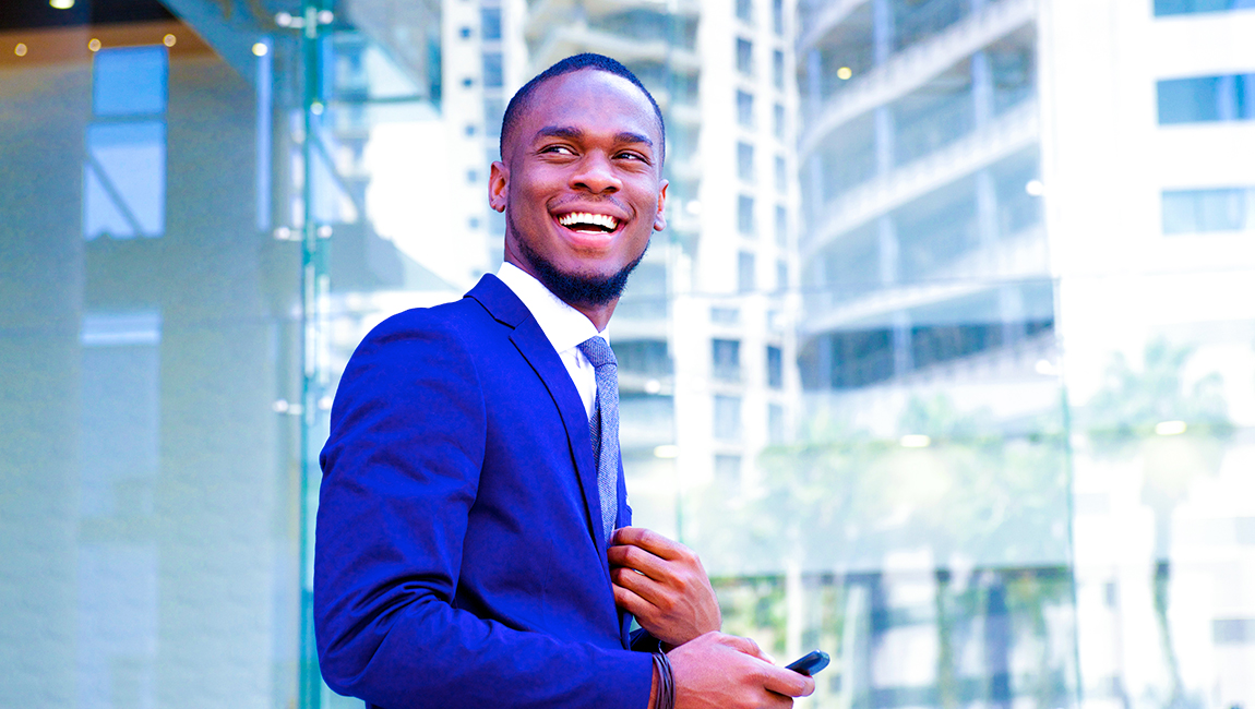 Smiling businessman wearing blue suit standing outside office buildings