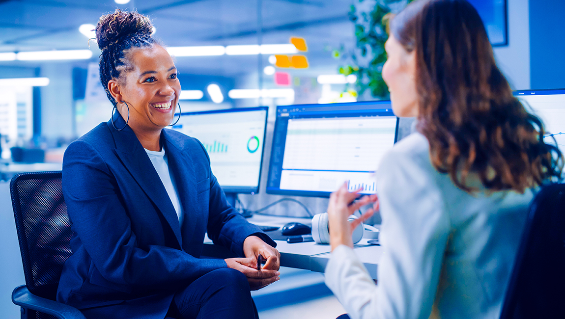 Two colleagues chatting at their desks
