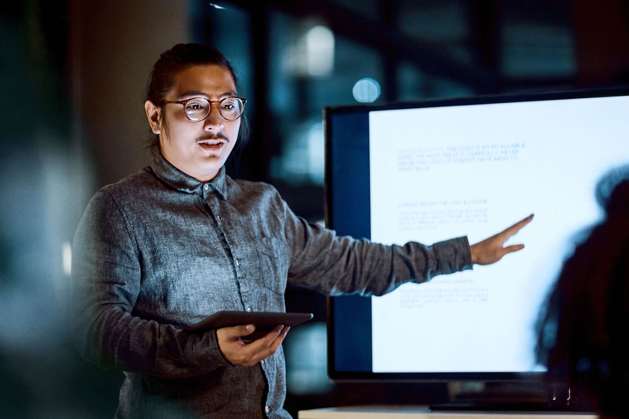 Businessman presenting with a tablet in front of a digital presentation