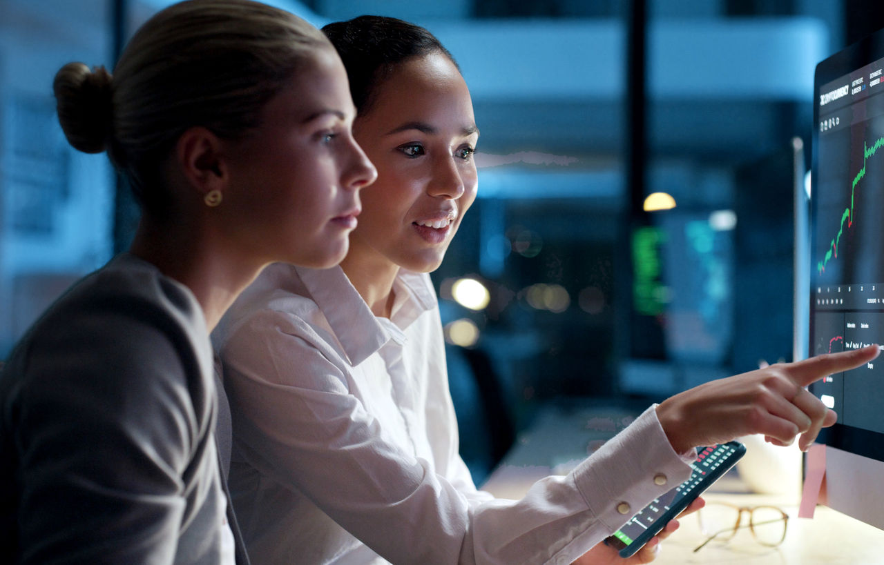 Two businesswomen discussing information on a computer screen