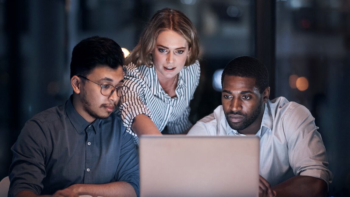 Three colleagues studying information on a laptop screen