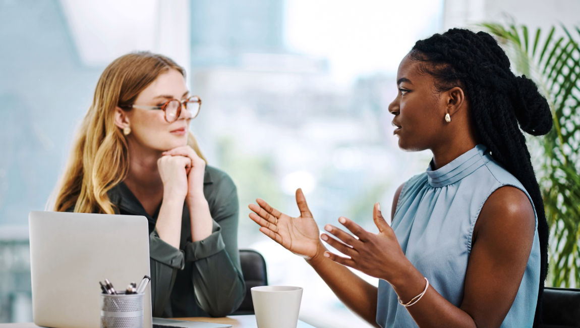 Two businesswomen speaking at a table