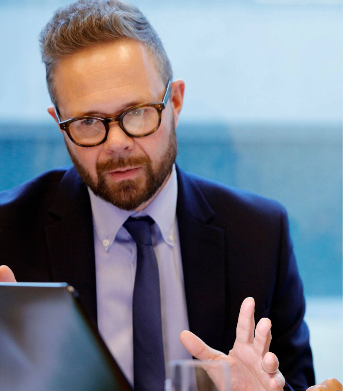 Businessman wearing glasses looking at laptop screen and analyzing