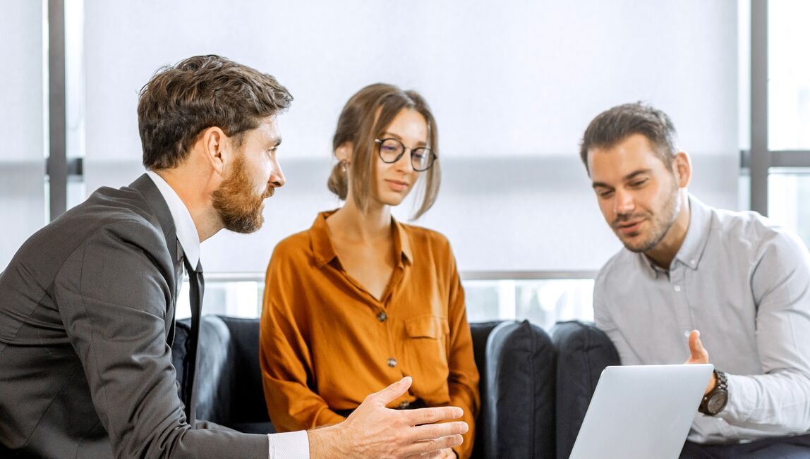 Three colleagues having informal discussion around a laptop
