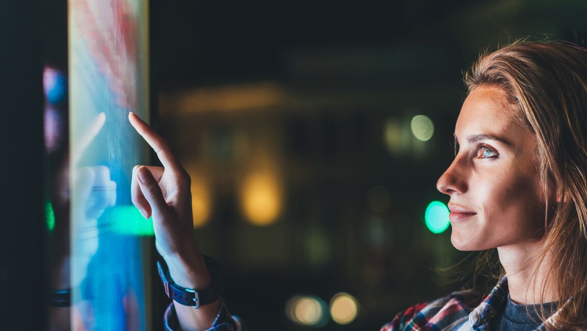 Businesswoman pointing finger at monitor display in dark office