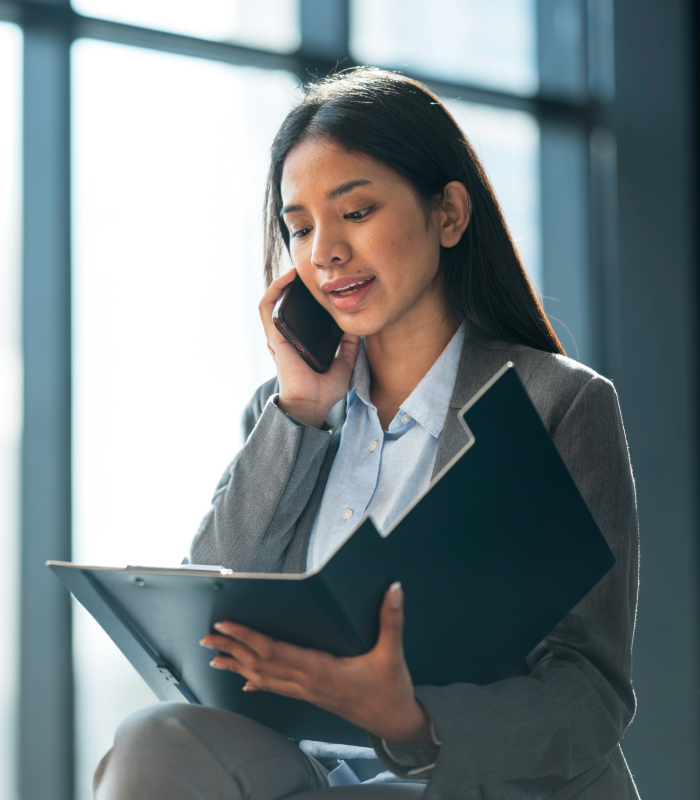 Business woman talking on phone while holding portfolio