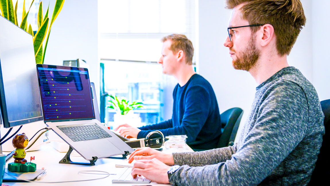 Two male colleagues sitting at their desks in open office floor plan